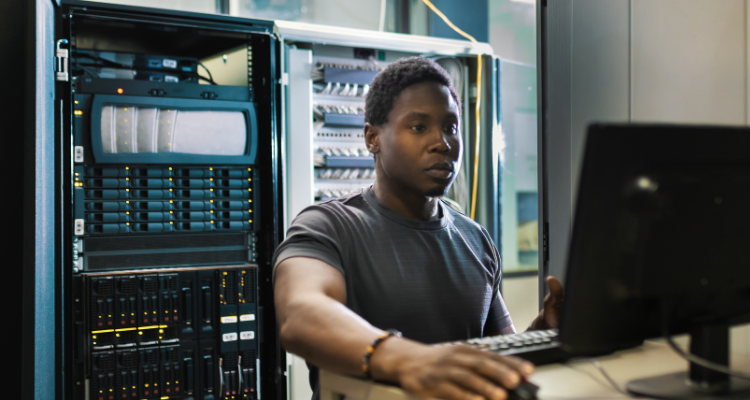 male standing at computer in data center