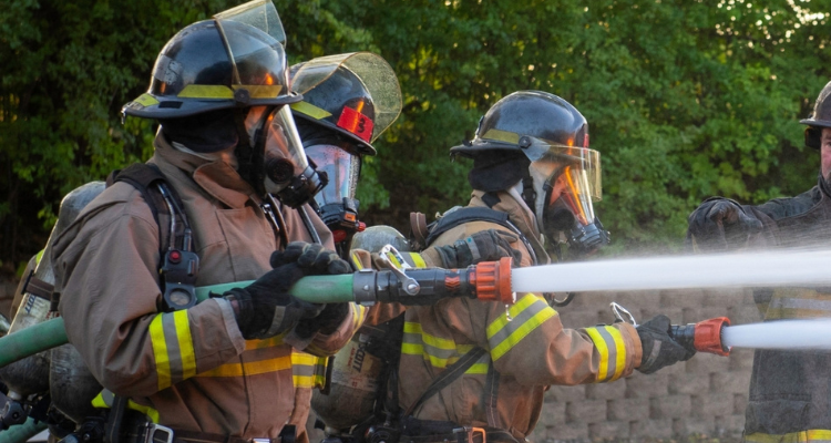 group of firefighters holding a hose with water coming out