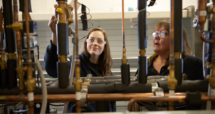 female student looking at mechanical pipes