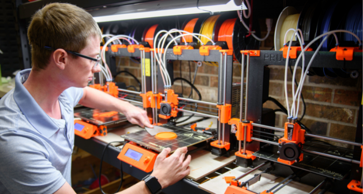 male student working with a commercial 3D printer