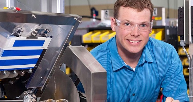 male student setting up machine for production