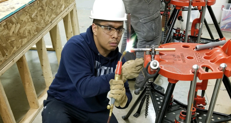 plumbing student sweating pipe fittings together