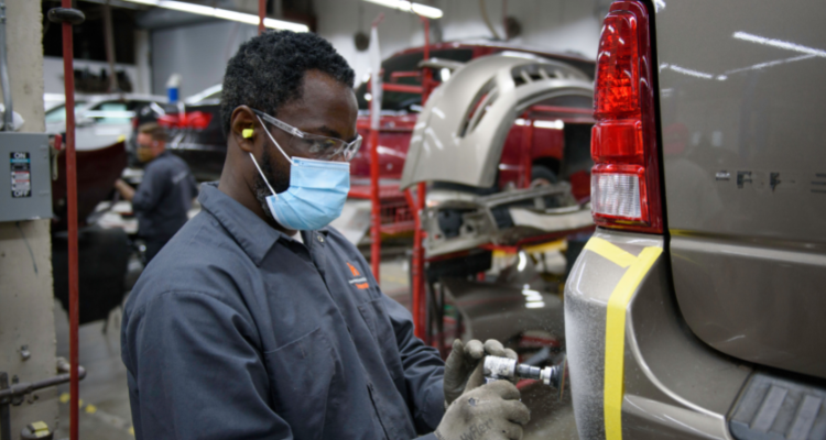 Man spray painting the rear bumper of a car