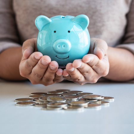 female holding a blue piggy bank in hands