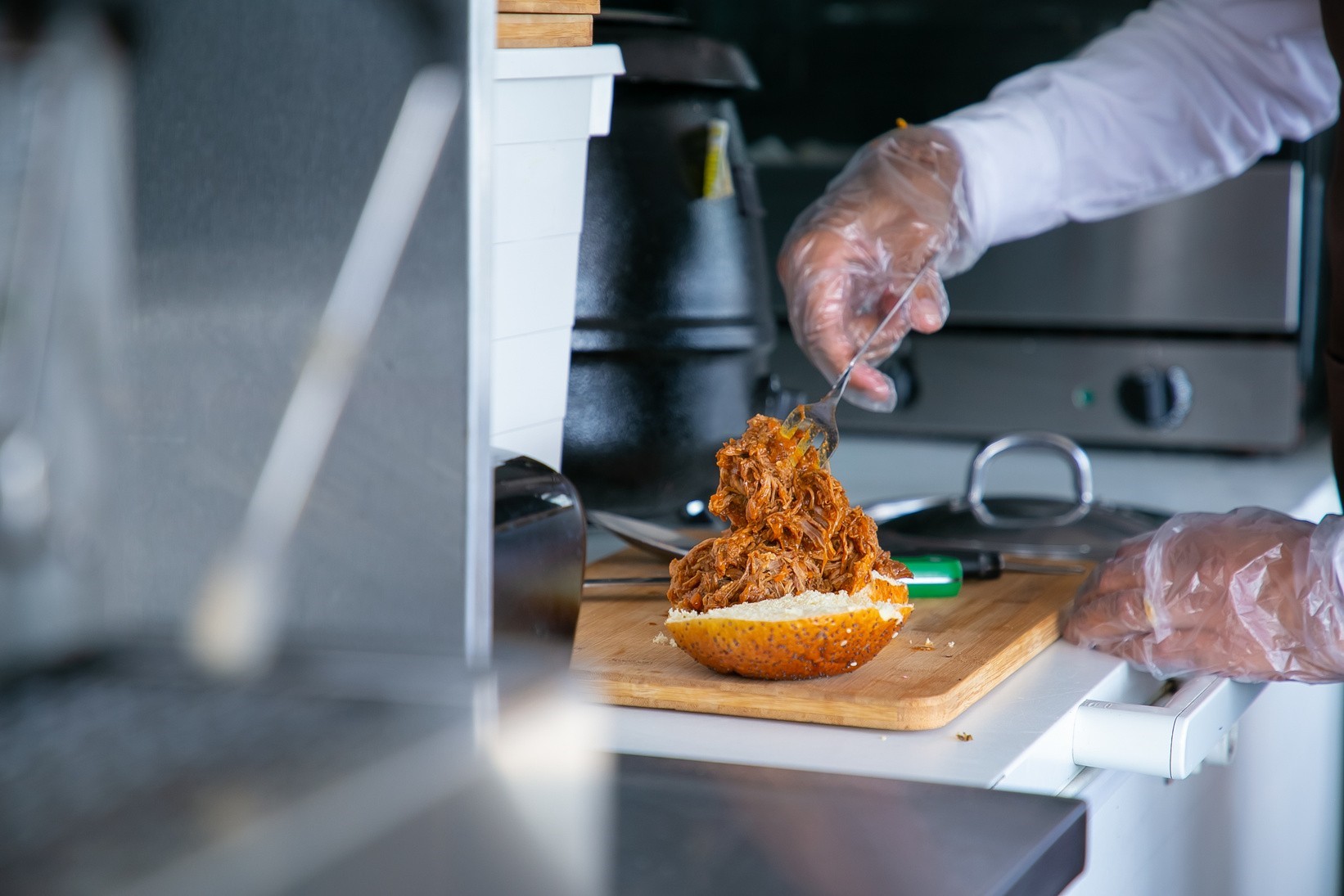 cook preparing fried chicken sandwich in a kitchen