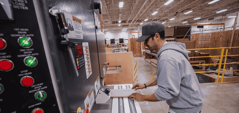 male student cutting wood board with carpentry lab equipment