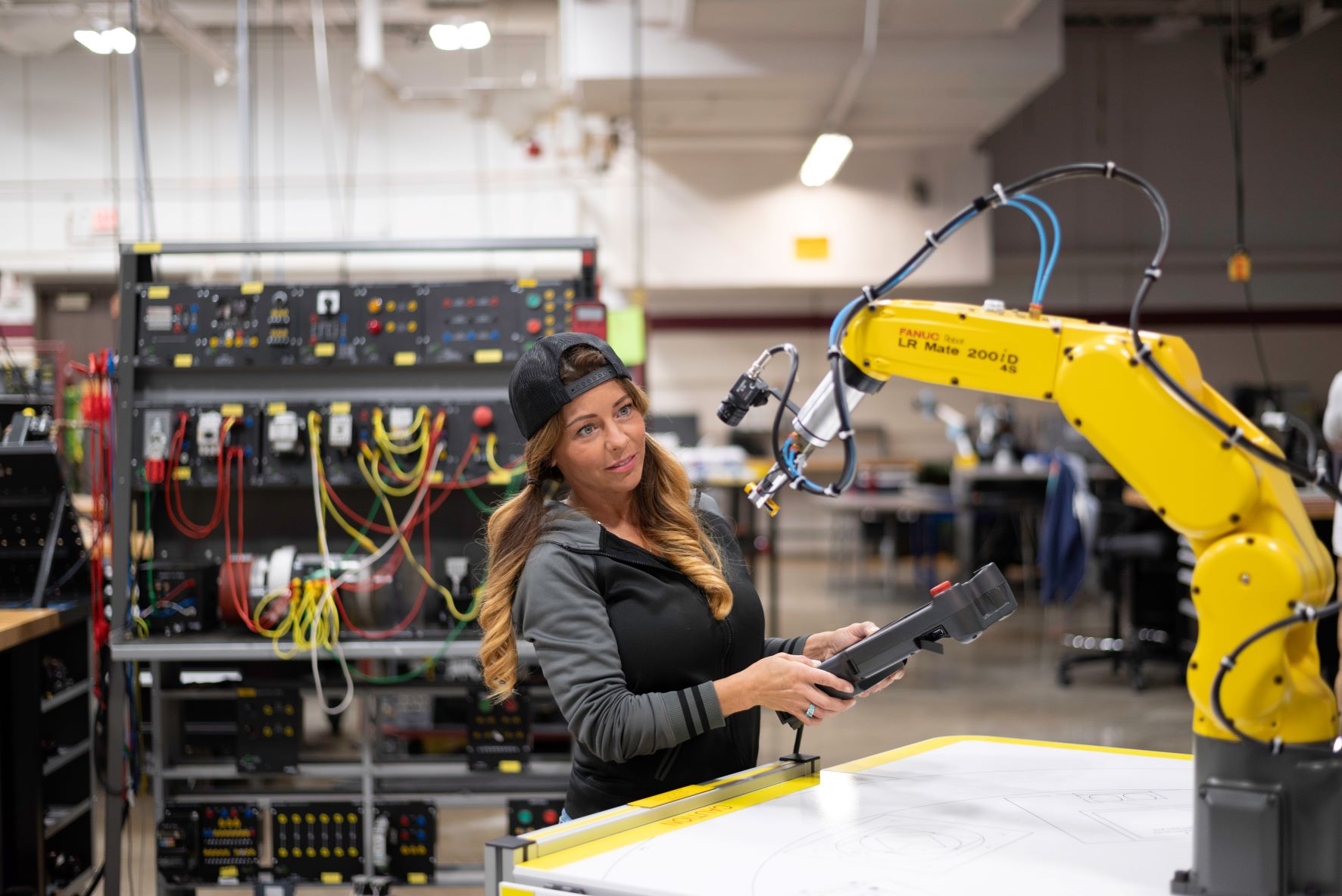 Female robotics student working with remote control and robotic arm